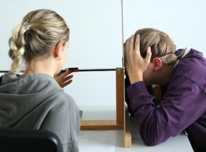 Zwei Studierende der Bionik bei der Durchführung eines Optik-Versuchs. Links schiebt die Studentin einen Regler auf einer Schiene. Rechts sitzt ein Student mit auf den Tisch gestellten Armen und schaut durch ein Loch in einer Platte auf den Regler.
